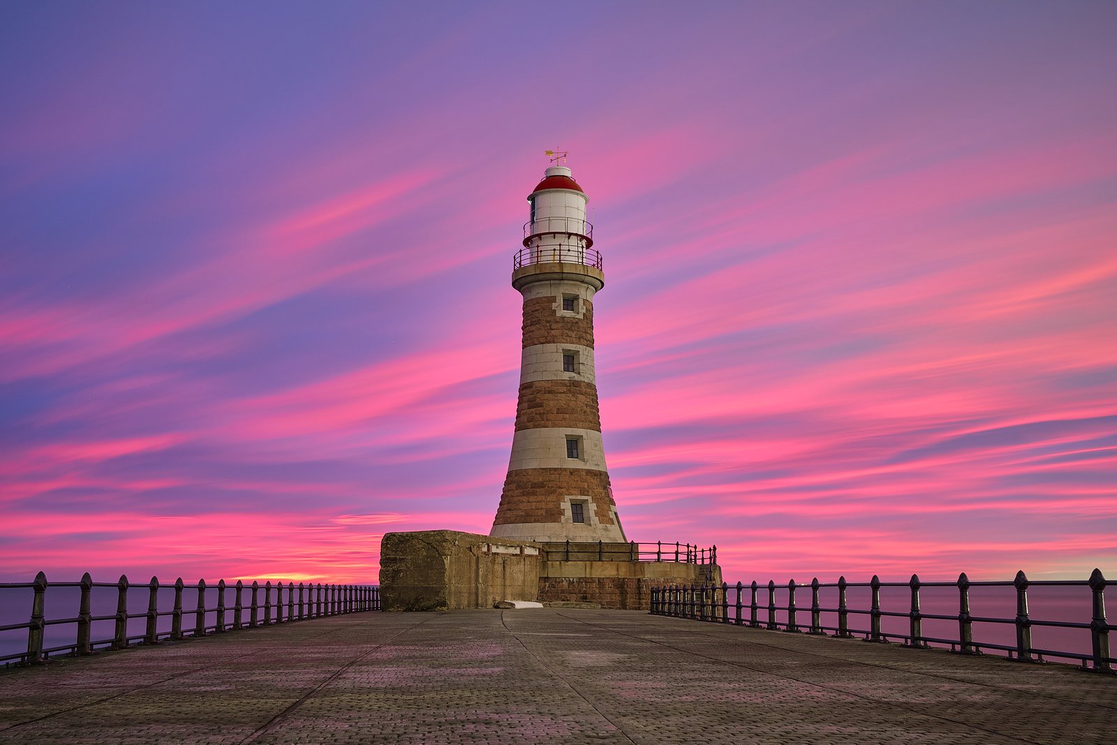 Roker Pier lighthouse at sunrise with calm sea and warm sky